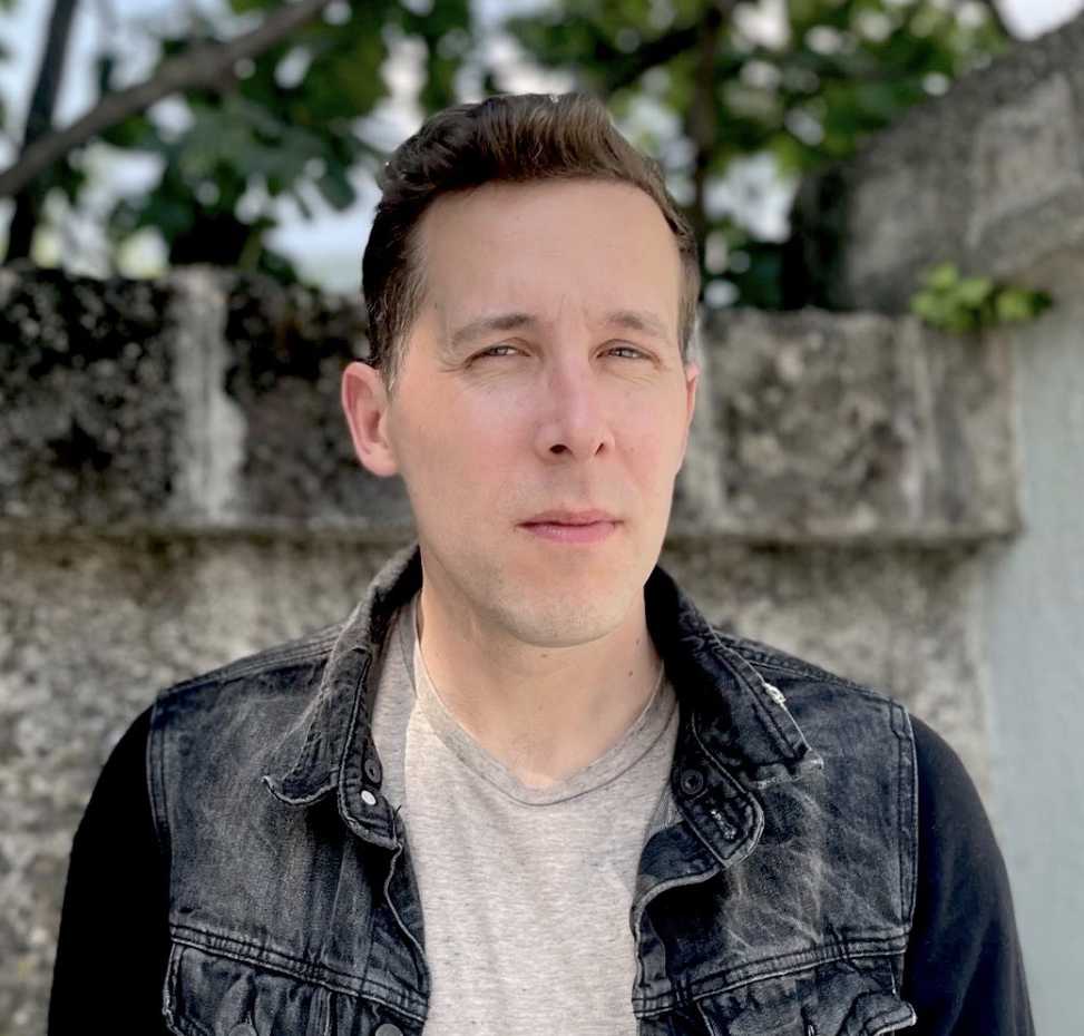 A portrait of Drake Andersen, a person with short brown hair and a dark denim jacket.