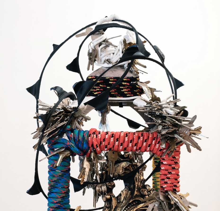 A photo of an abstract sculpture constructed from assorted materials, including lots of metal keys and colored rope.
